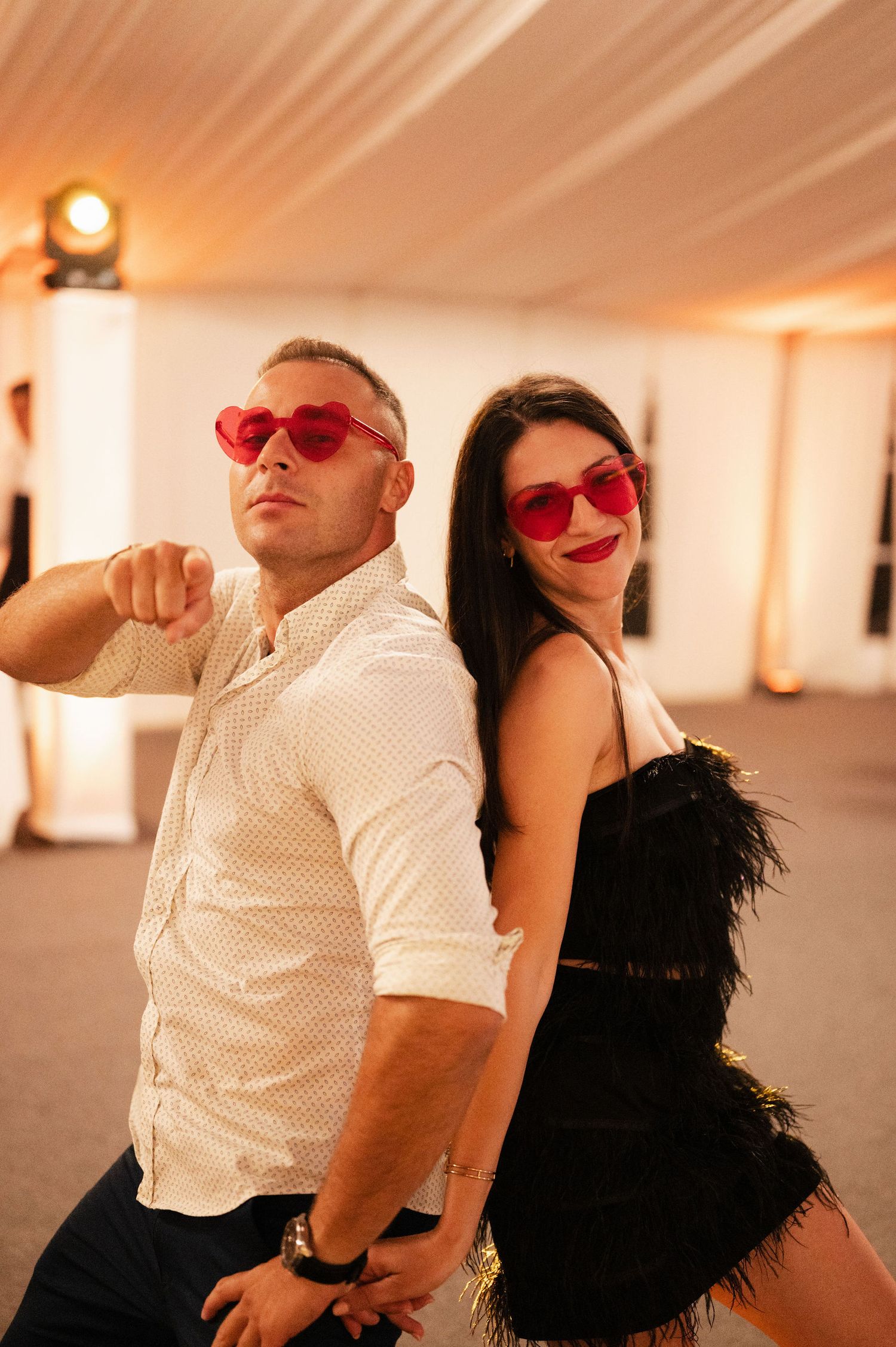 A couple in red sunglasses pose playfully in a series of four connected photos with warm lighting.