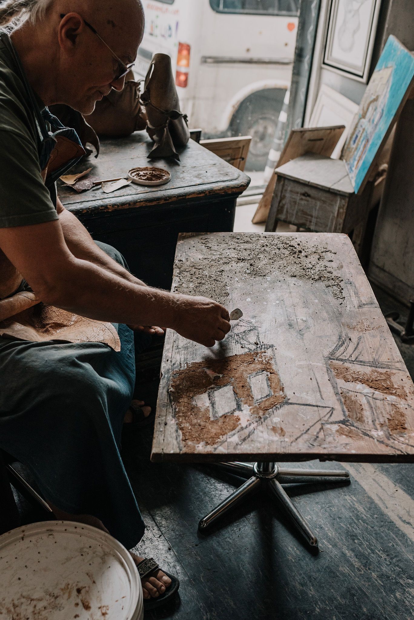Close-up of hands working on a textured surface in a workshop setting.