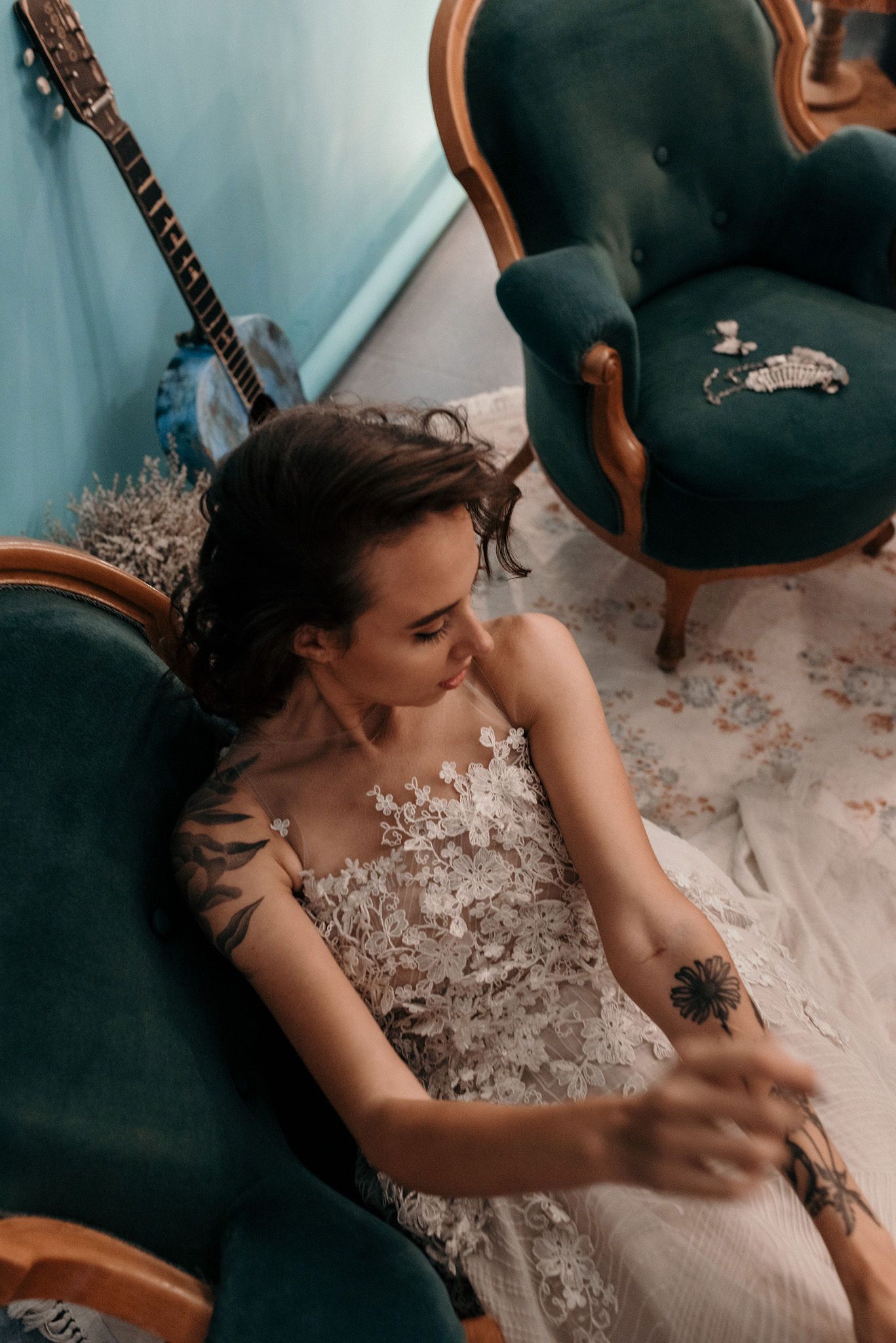A stunning white lace wedding dress with intricate floral details photographed against a turquoise background.