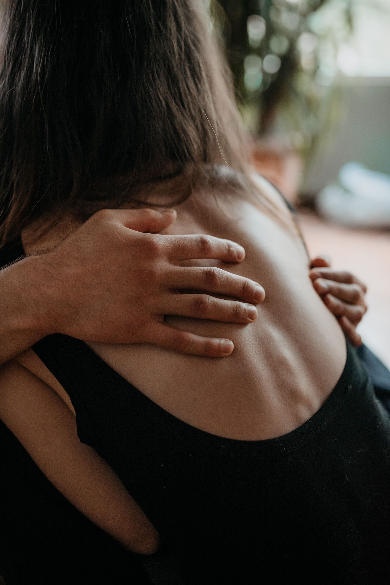 Close-up shot of hands gently embracing shoulders in an intimate moment.