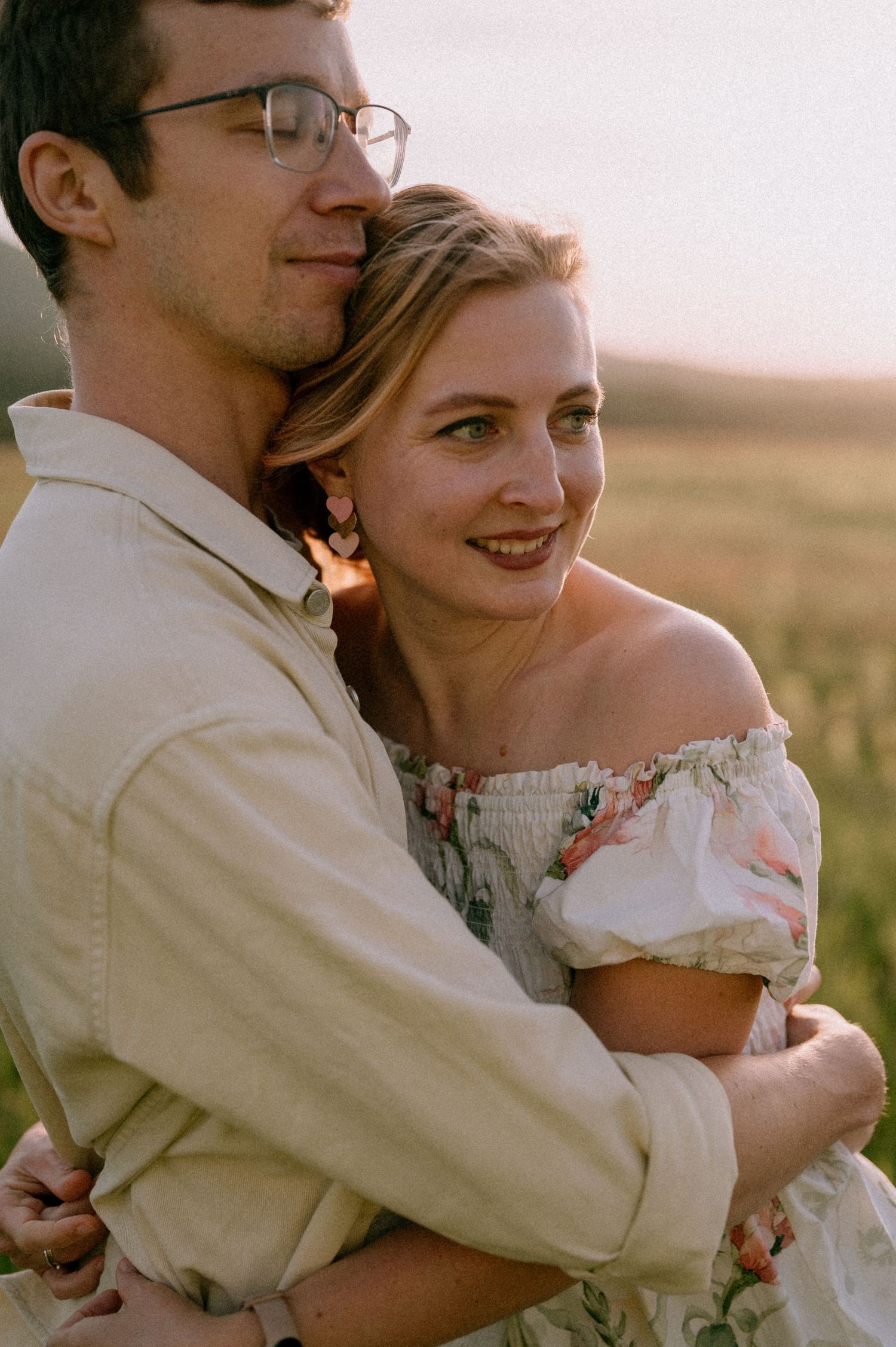 A romantic embrace between a couple in a field during golden hour.