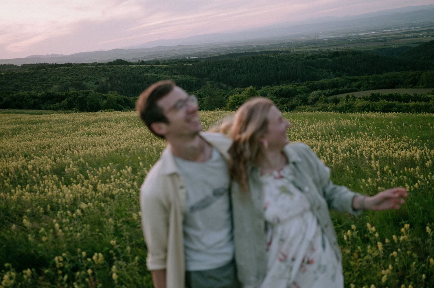 Two people share an intimate dance moment in a wildflower field as the sun sets.