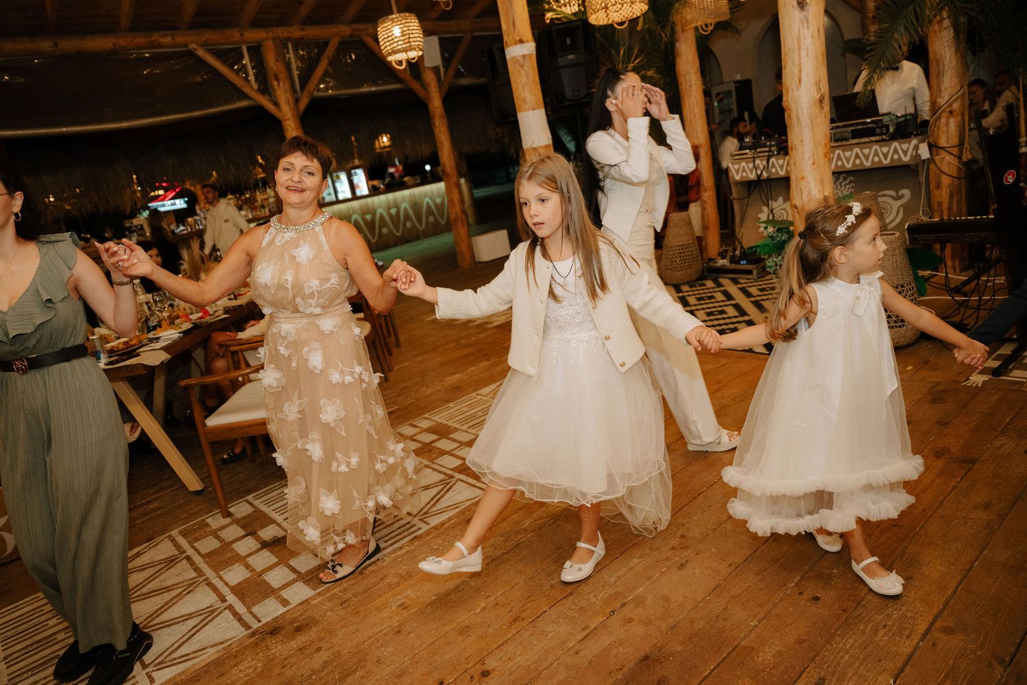 People dancing and celebrating at a rustic outdoor wedding reception with warm lighting and festive atmosphere.
