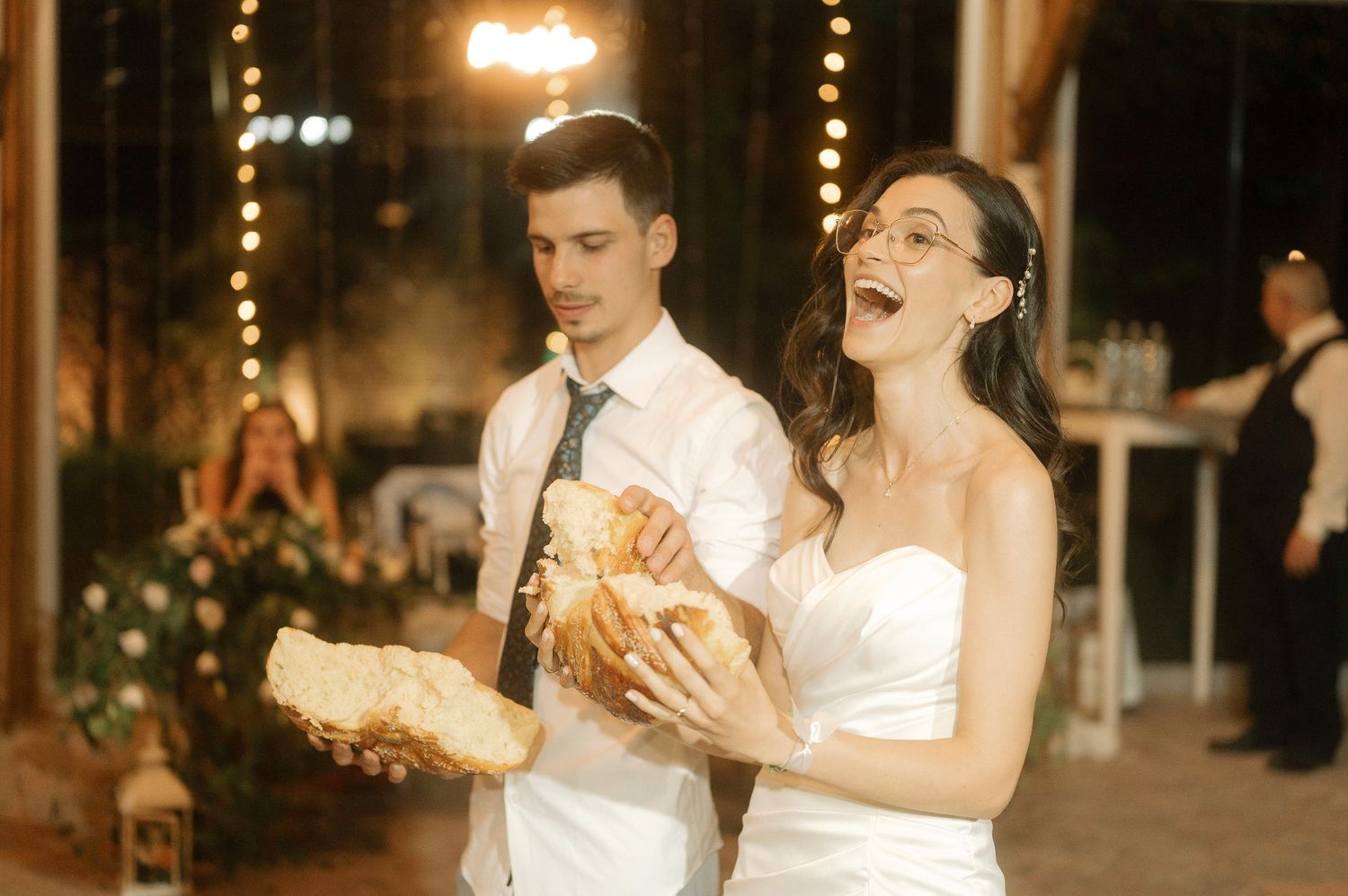 A couple shares their first dance at an elegant evening wedding reception with warm lighting and festive decorations.