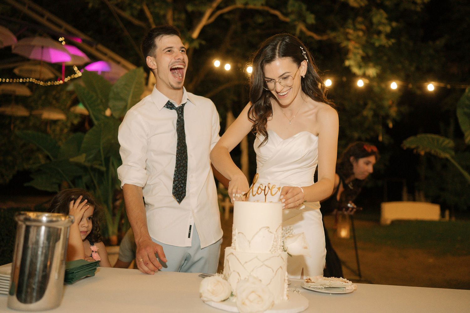 Guests dancing and celebrating at an outdoor evening wedding reception under string lights.