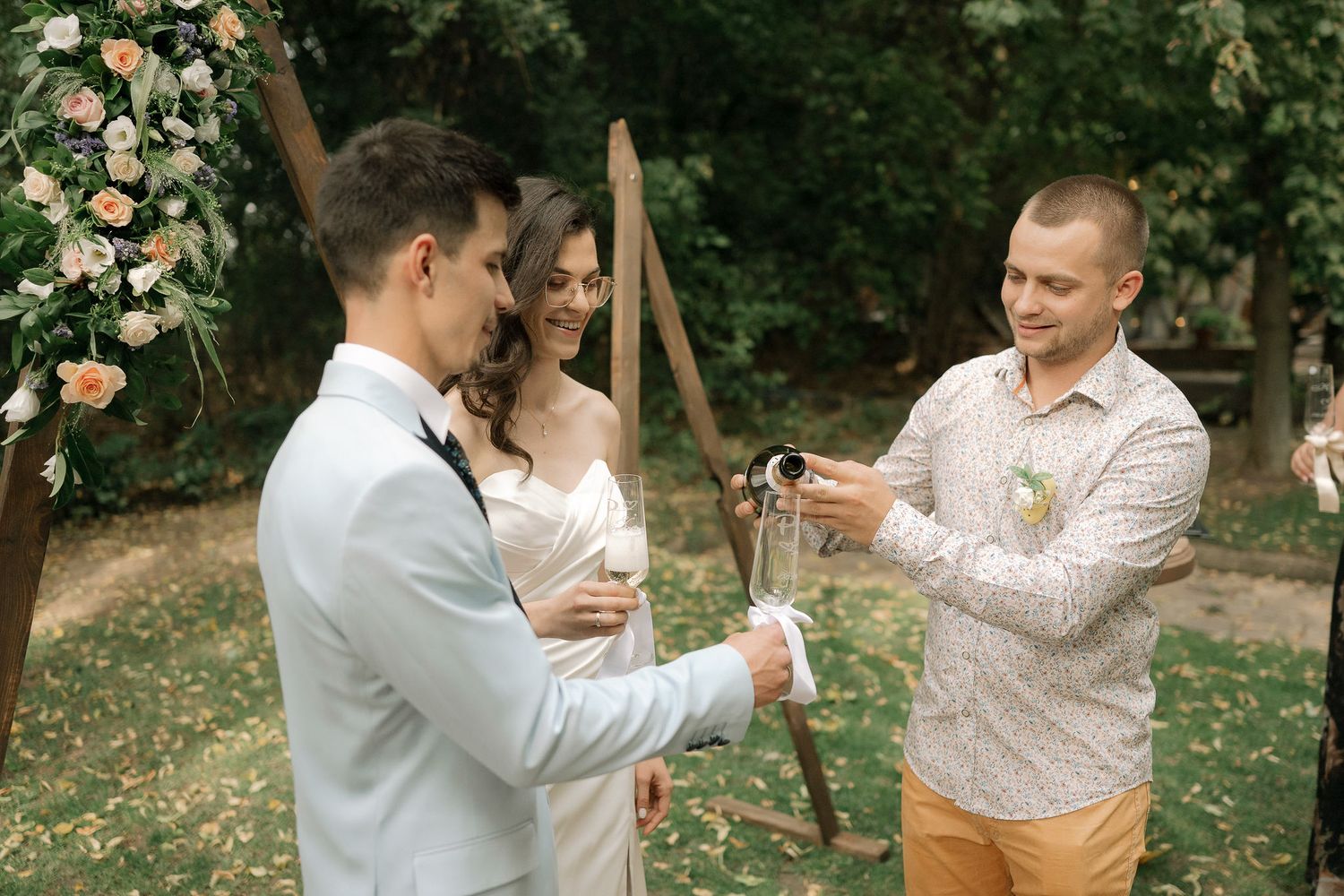 Two people dancing together in an outdoor garden setting surrounded by blooming flowers and trees.