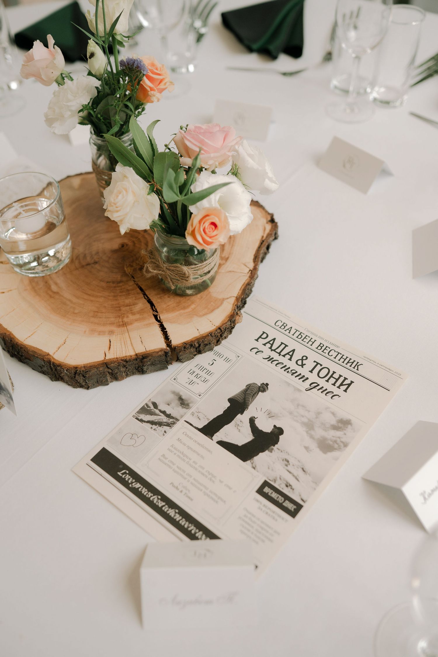 Rustic wedding place cards with black silhouettes displayed on wood slices with peach roses and greenery centerpieces.