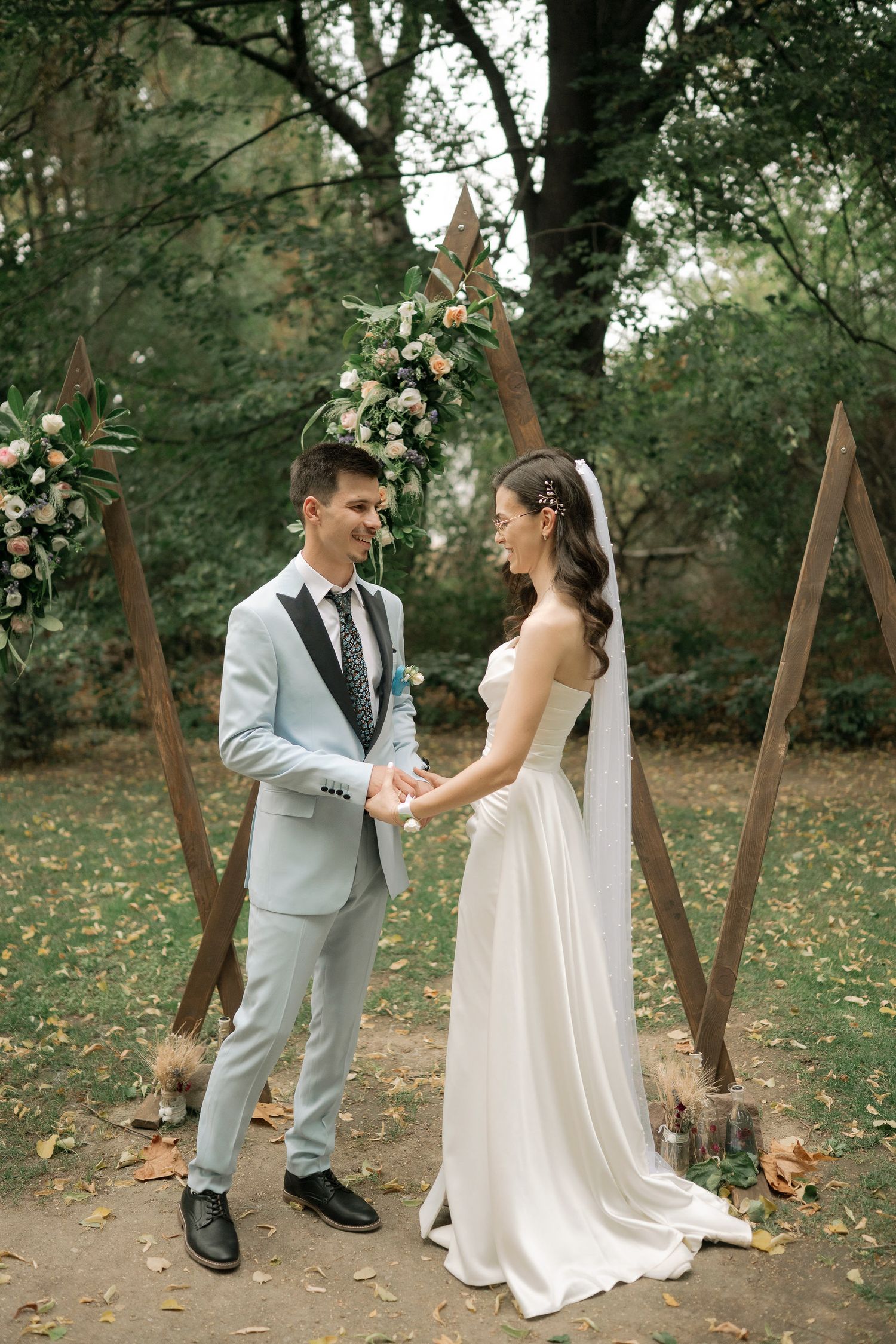 A couple shares a joyful moment together in a wooded outdoor setting during their wedding celebration.