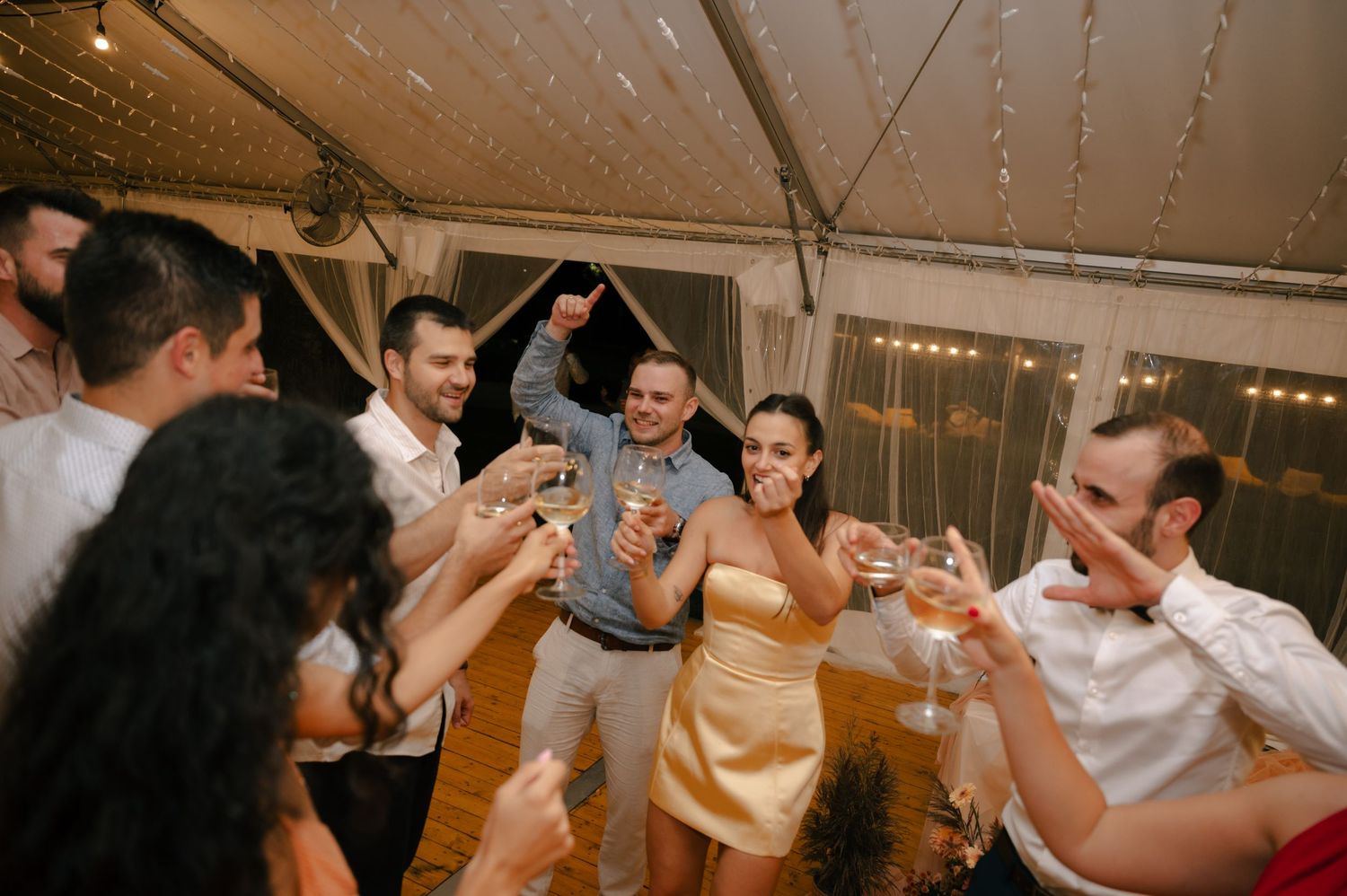 Guests dancing and enjoying themselves at an indoor wedding reception with decorative lighting.