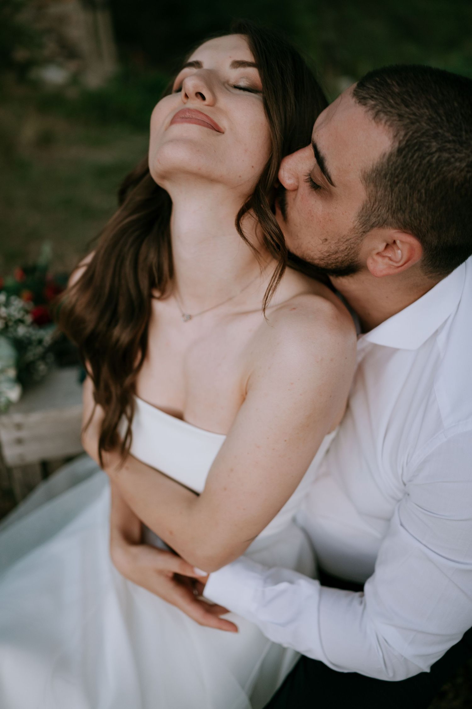 Tender moment captured between newlyweds in an intimate outdoor setting.