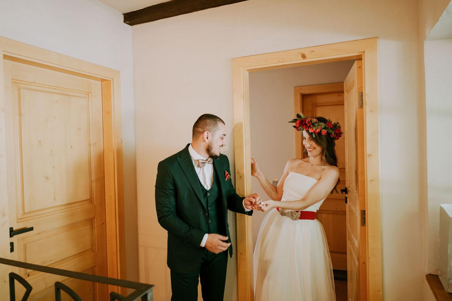 An emotional first look between newlyweds in a room with wooden beams and natural light.