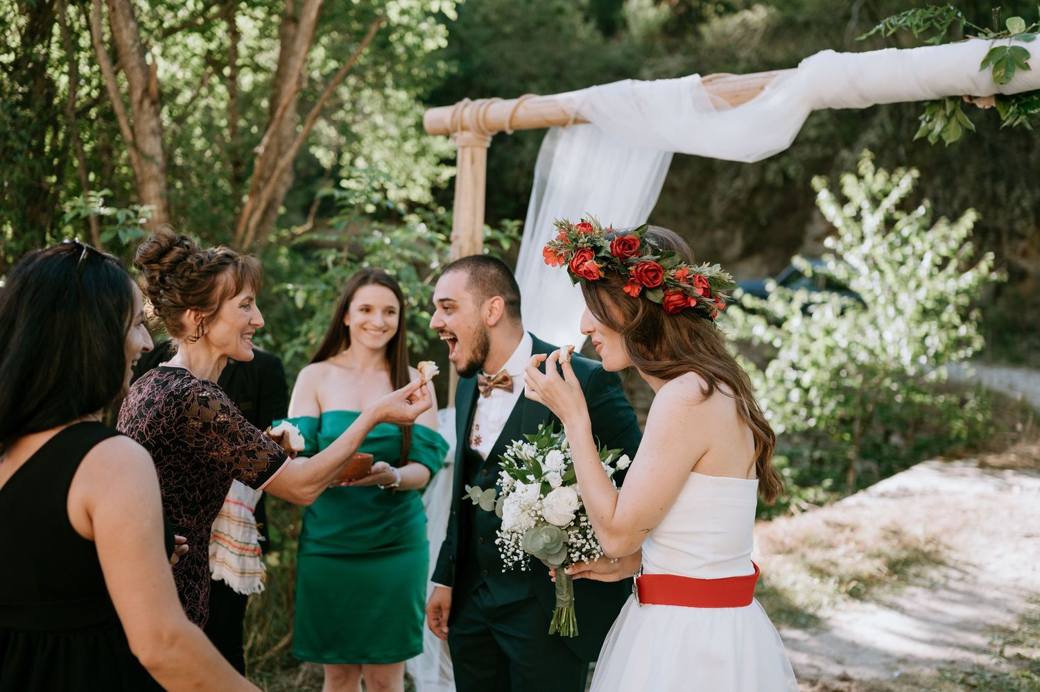 Wedding celebration with guests gathered in garden setting near stone building.