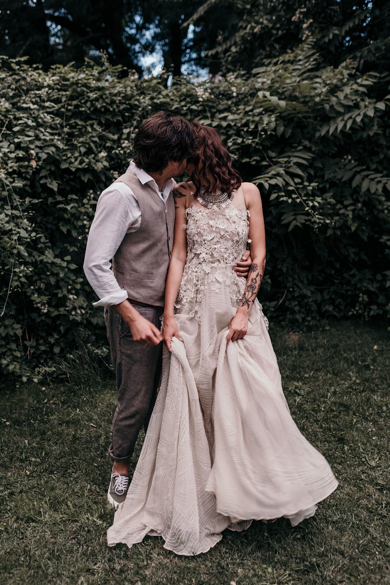 A series of candid moments showing a couple in wedding attire walking and interacting on a grassy lawn with trees in background.
