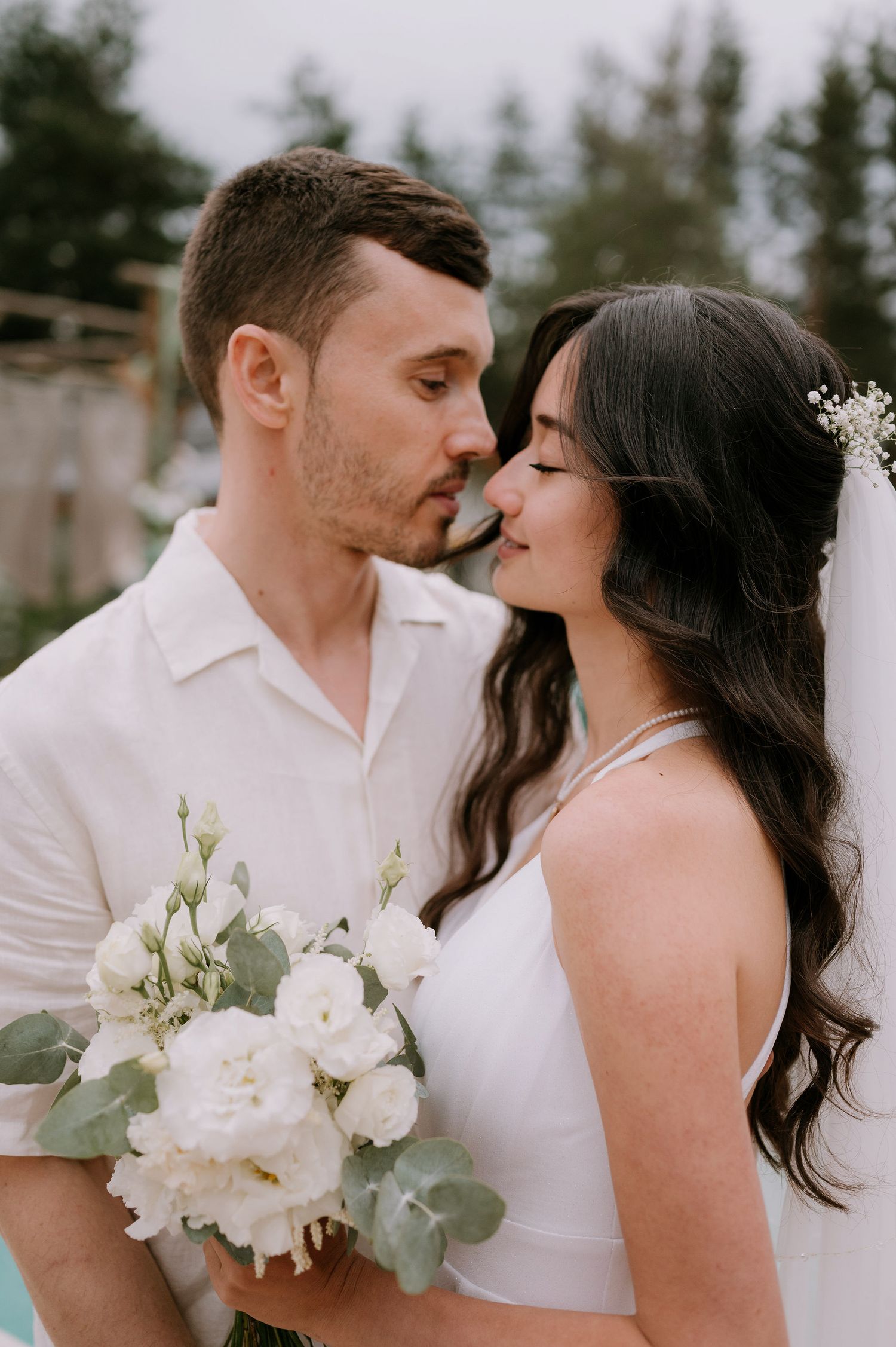 Intimate wedding moment captured poolside with white florals and eucalyptus bouquet.