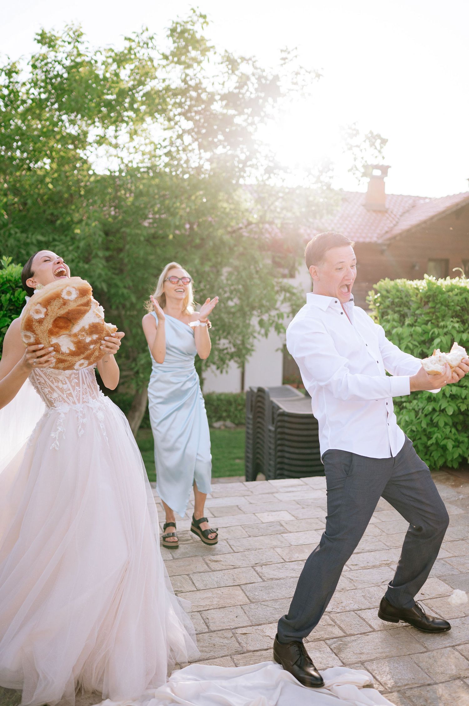 Dancers perform energetic moves on a stone patio during an outdoor celebration.