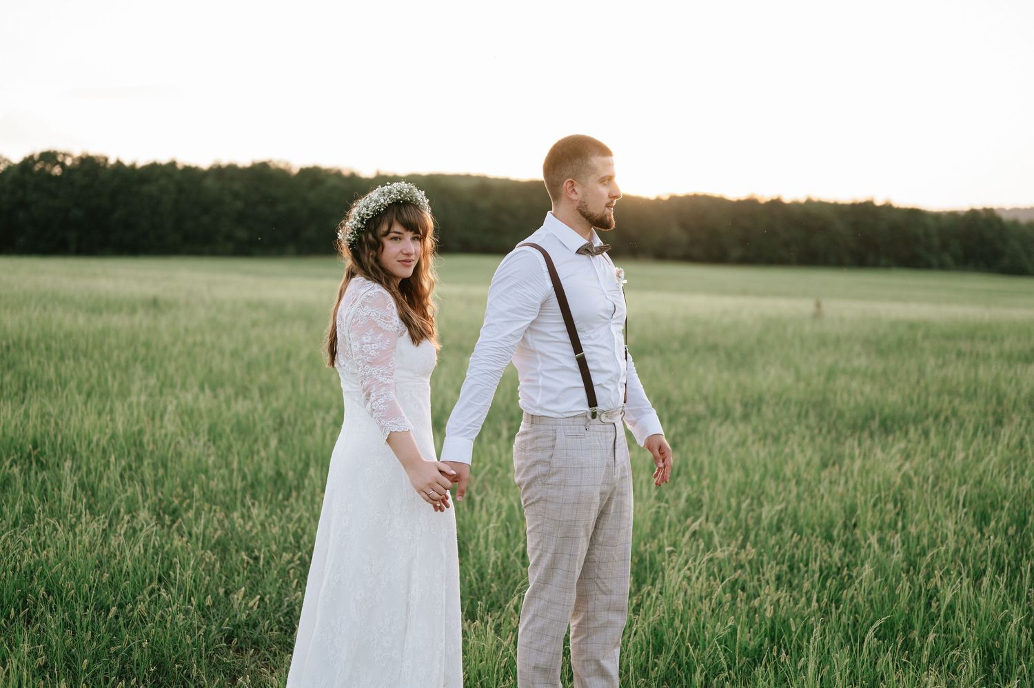 A couple poses together in a serene field during their rustic outdoor wedding shoot.