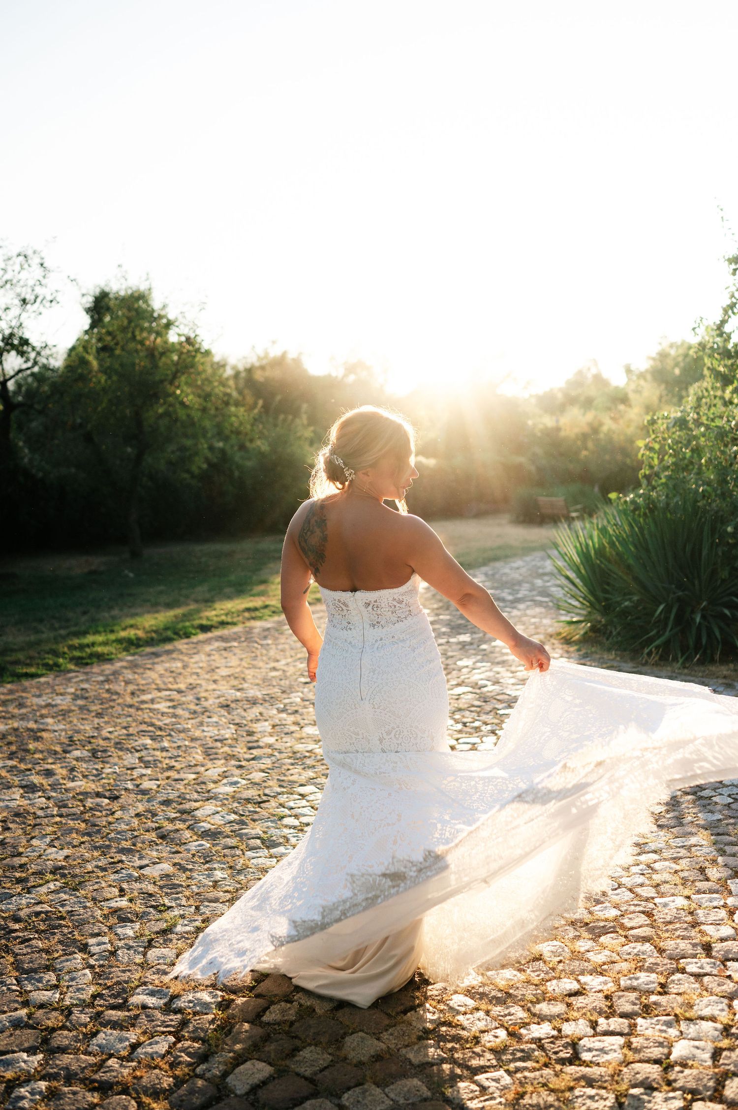 White bridal gown spreads elegantly across stone pathway during sunset photography session.