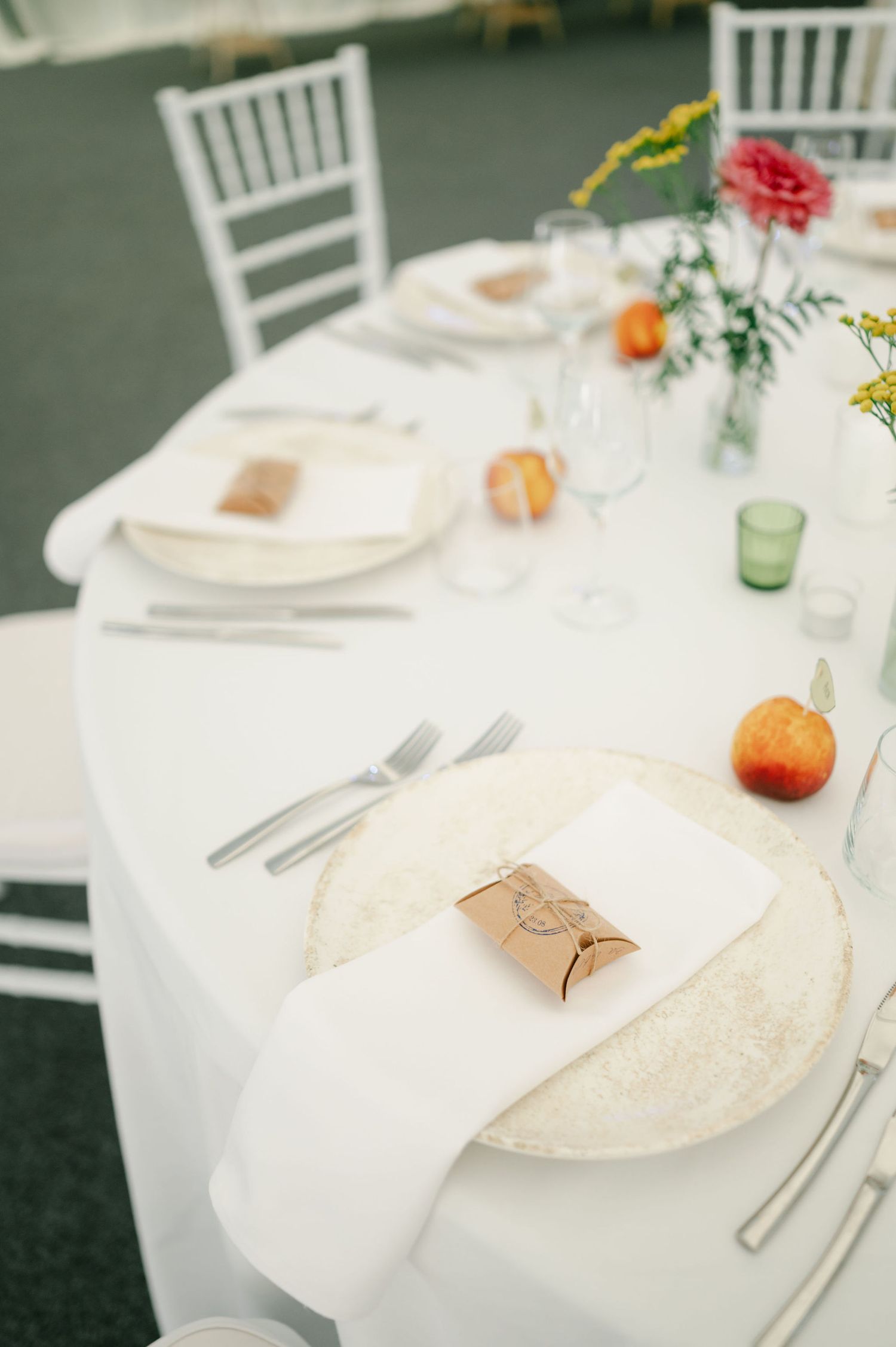 Wedding reception table settings with white chairs, linens, and colorful floral centerpieces.