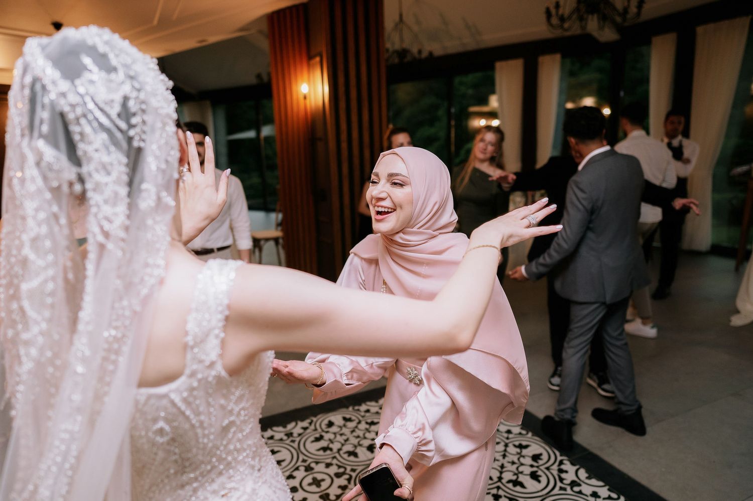 Joyful celebration at a wedding reception with guests dancing and embracing.