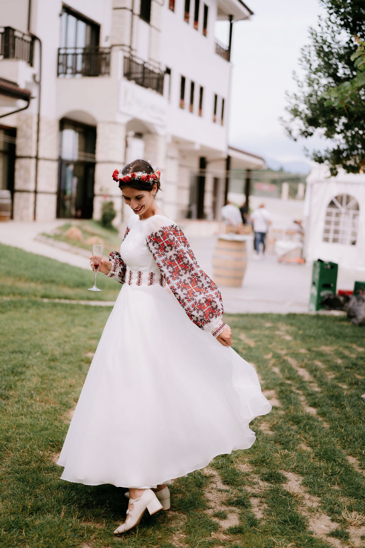 A flowing white dress with traditional red embroidered details spins in a courtyard setting.