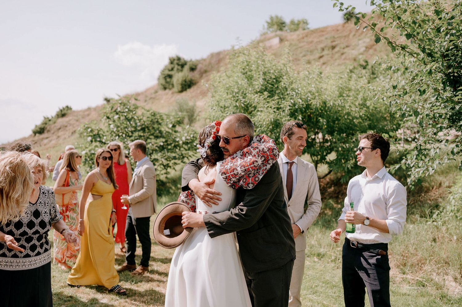 Wedding party poses for outdoor photos in a natural garden setting with greenery.