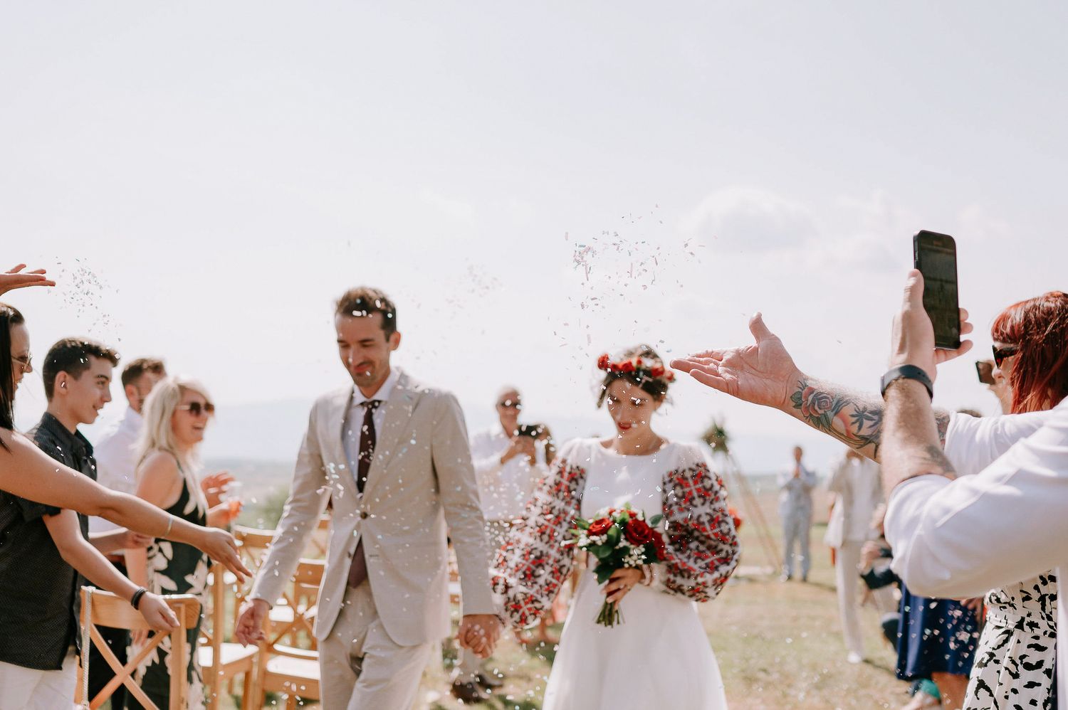 Wedding party and guests pose excitedly for photos on a scenic hilltop.