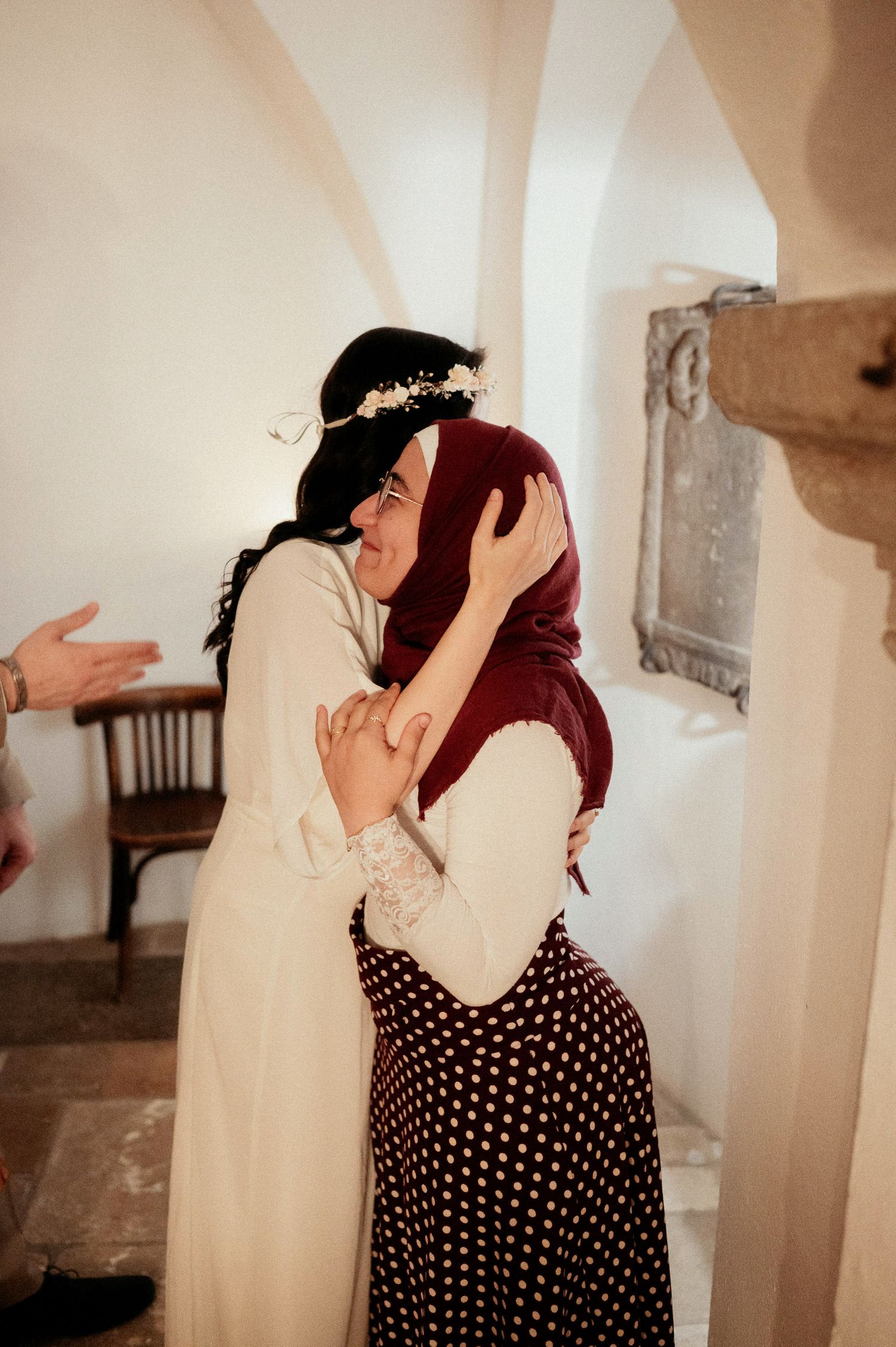 A couple embraces in a romantic moment against a light-filled archway interior.