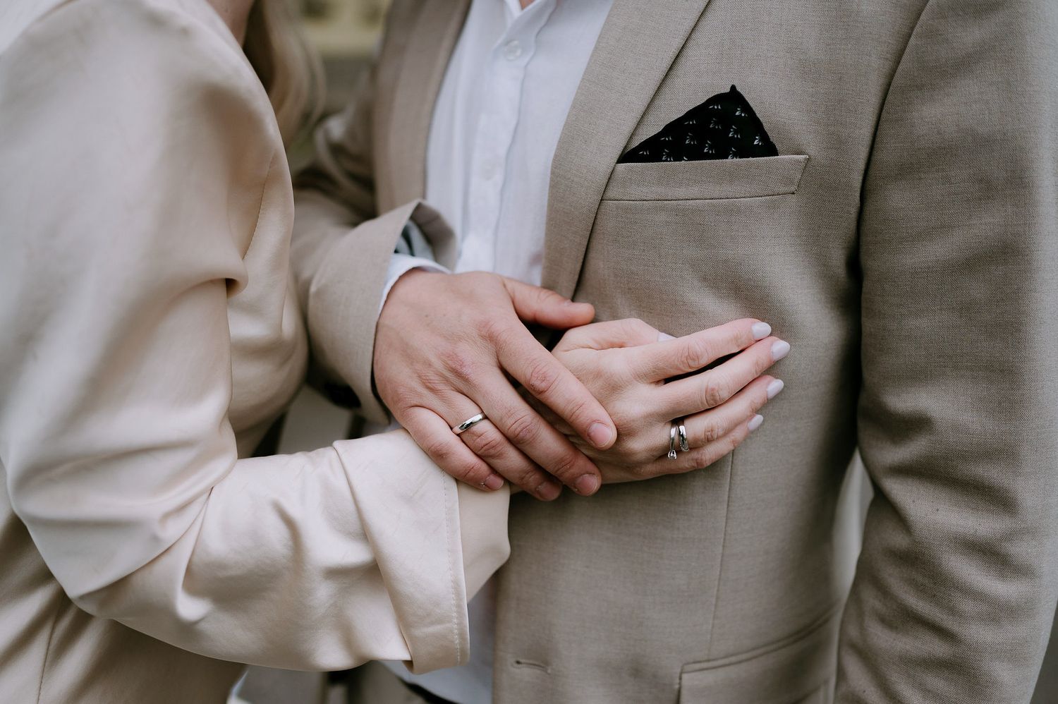 A couple in light colored formal attire embrace in an intimate moment.