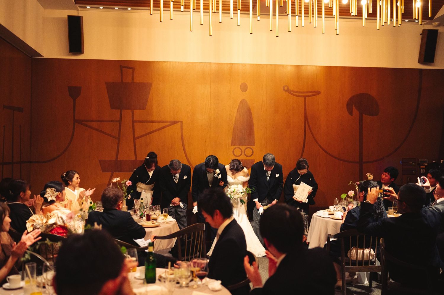 Wide angle shot of elegant reception venue with chandeliers and formal table settings.