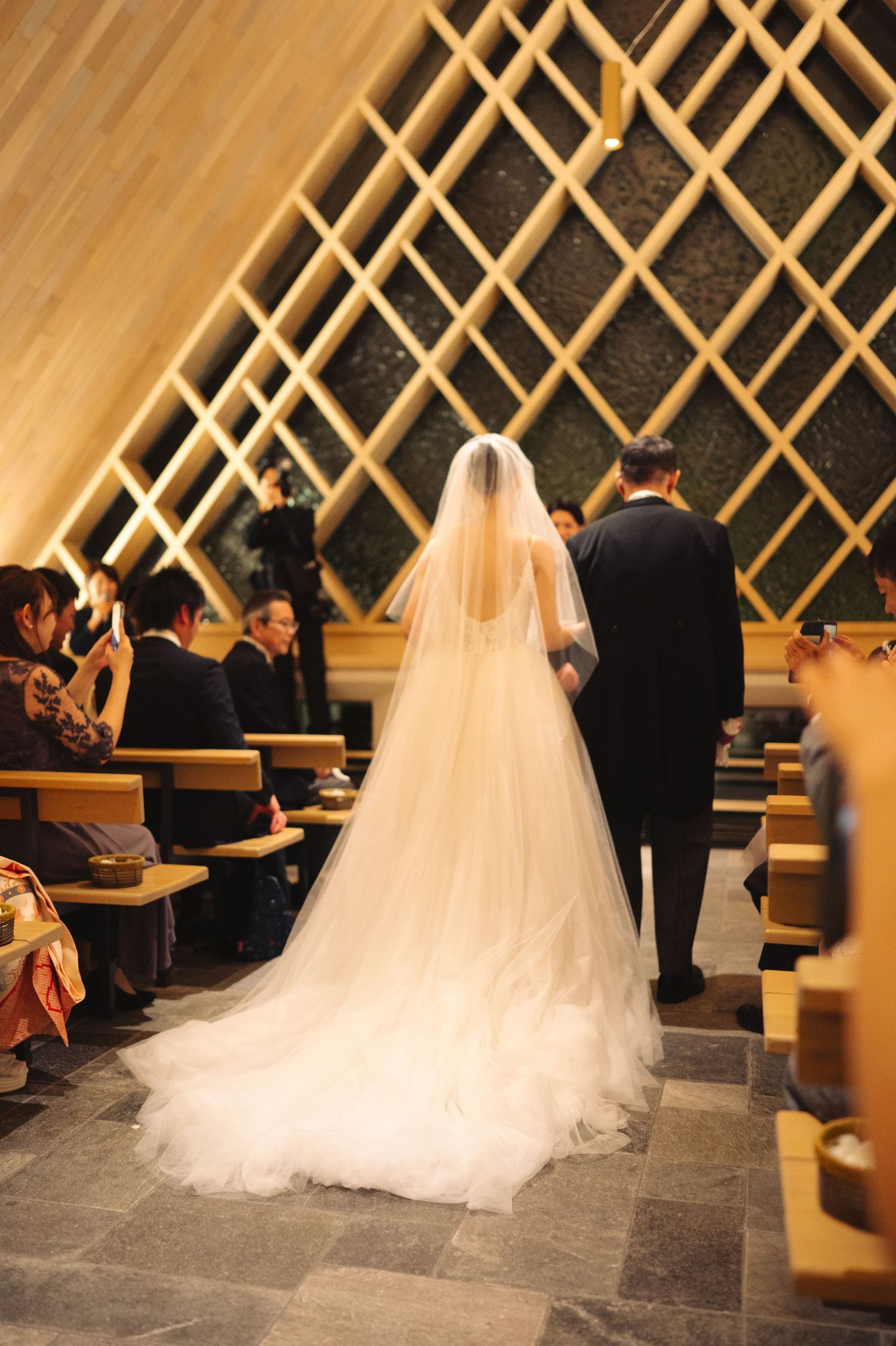 Elegant wedding ceremony in contemporary chapel with wooden lattice wall features.