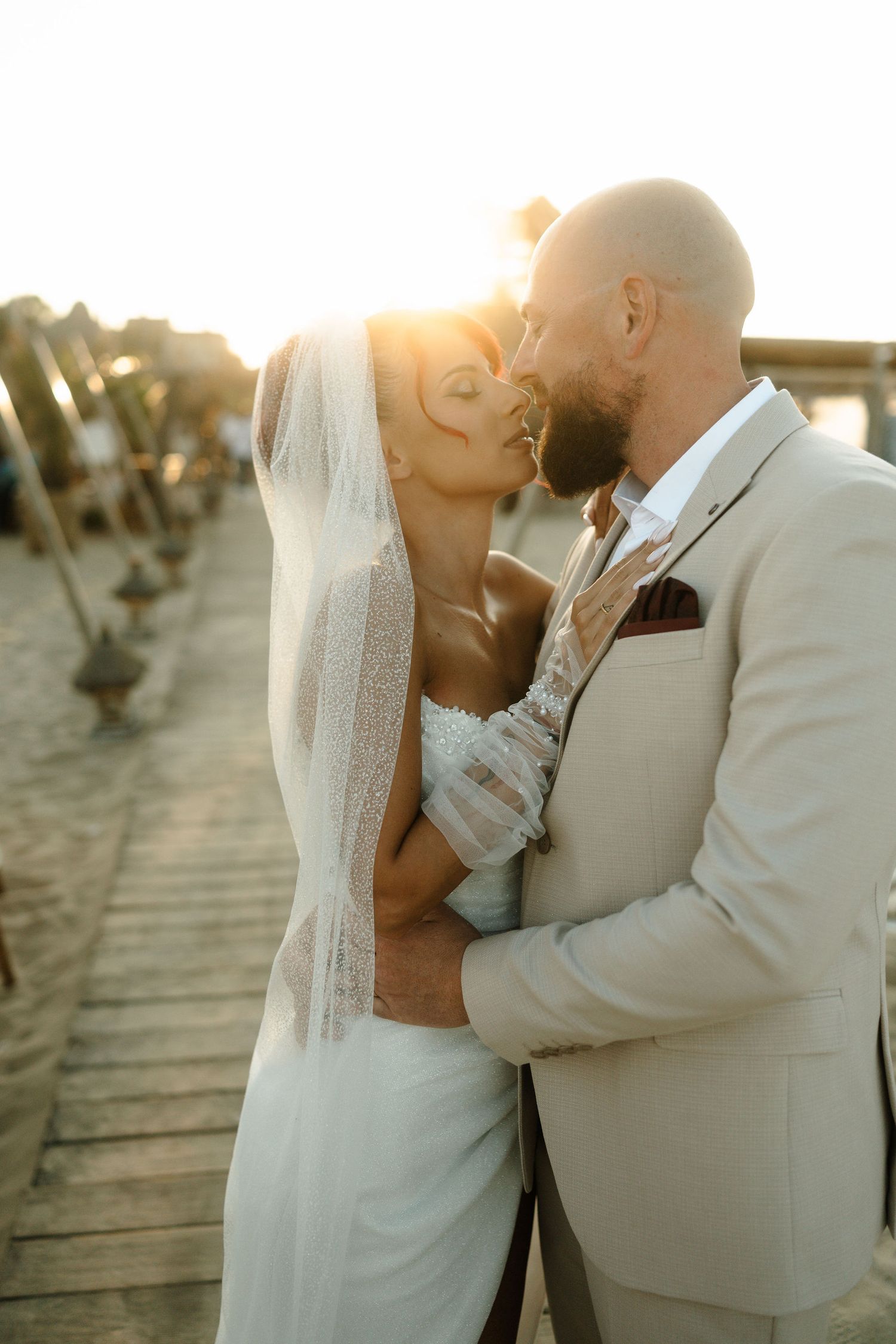 A romantic wedding couple shares intimate moments at sunset on a boardwalk in a series of connected photos.
