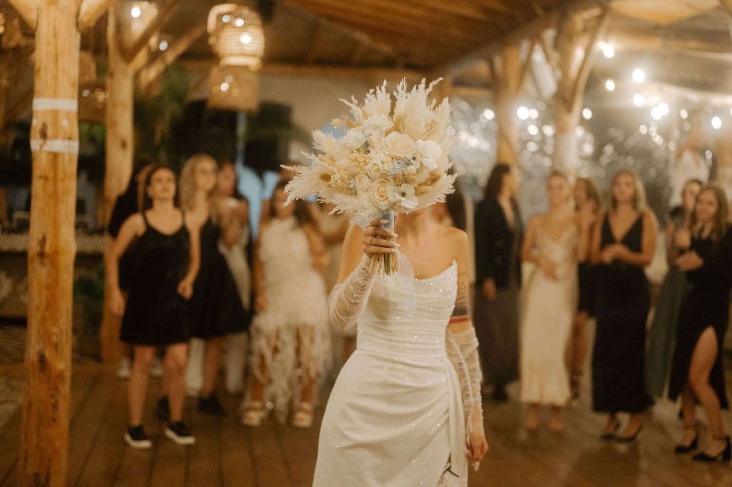 A bride and groom dance together at their rustic barn wedding reception surrounded by guests.