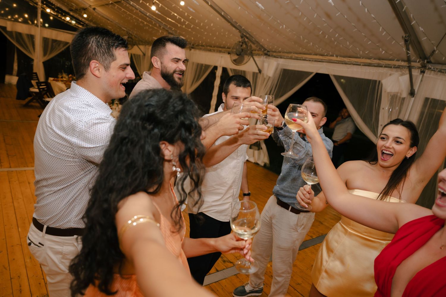 Wedding guests dance and celebrate together on a warmly lit dance floor during an evening reception.
