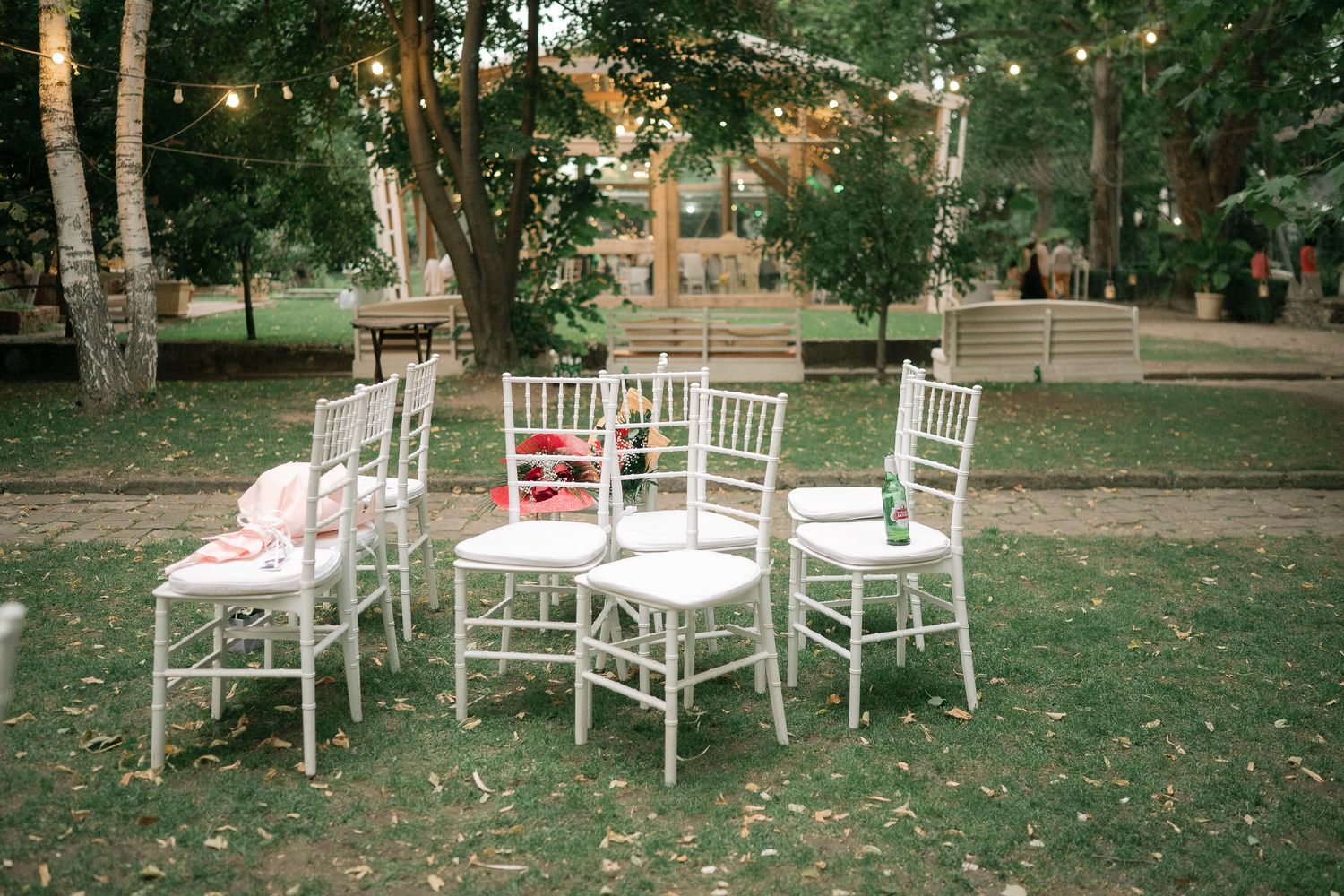 White wooden chairs arranged on a grassy lawn for an outdoor wedding ceremony or event.