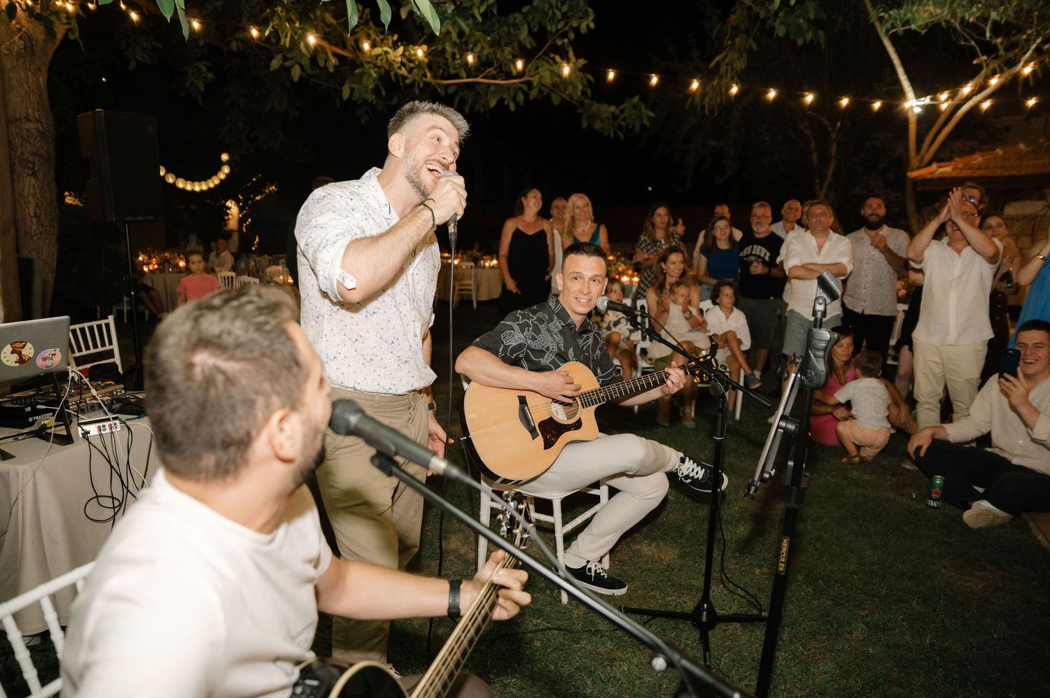 Partygoers enjoy live music and dancing at an outdoor evening celebration with ambient lighting.