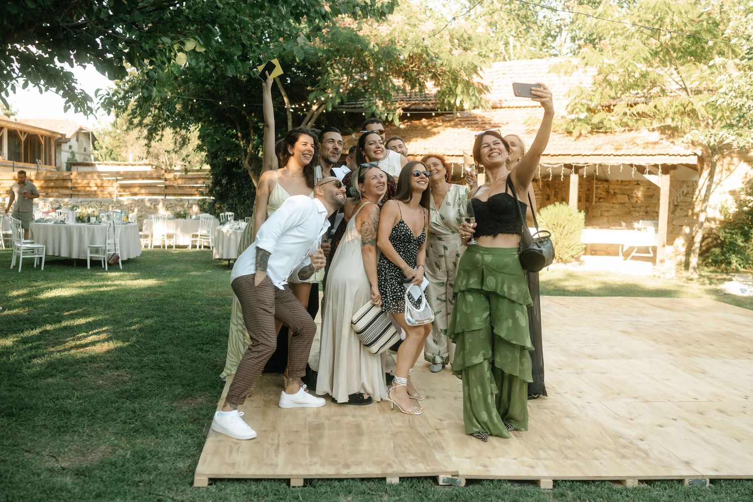 Wedding party members dancing together on an outdoor dance floor during a sunny celebration.