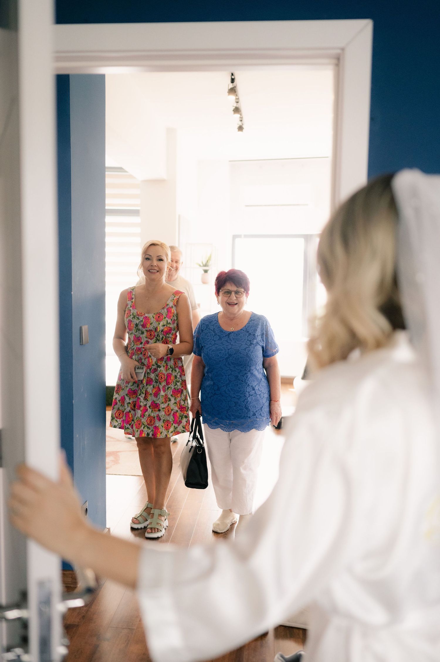 A sequence of photos showing people walking through a bright white hallway with blue walls.