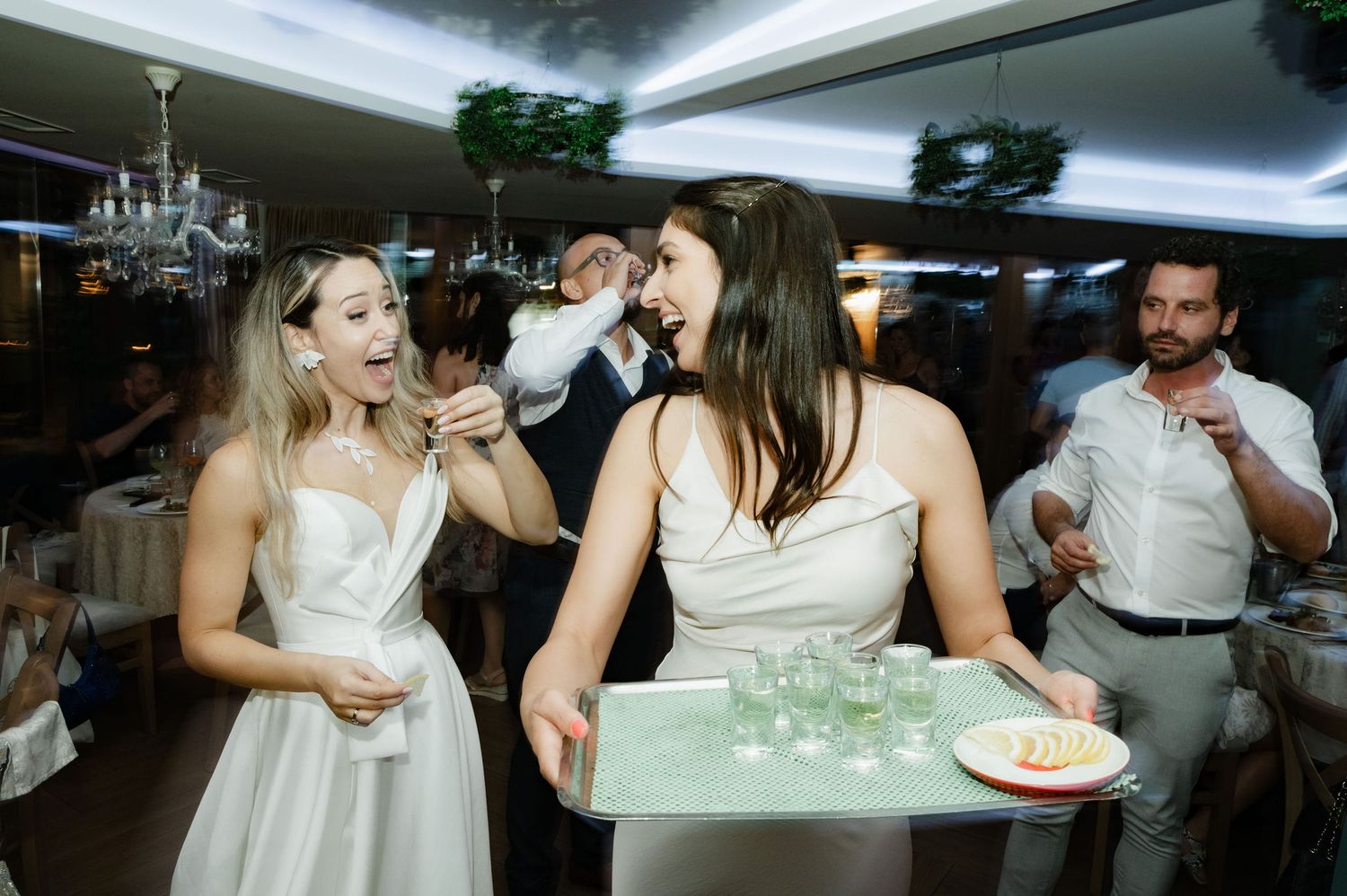 A group of wedding guests participate in a fun party game with dollar bills at a reception celebration.