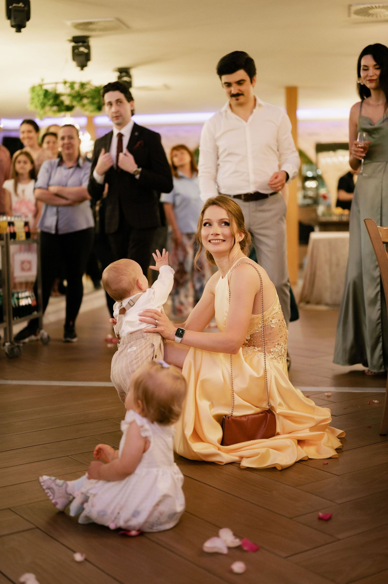 A sweet moment on the dance floor as a woman in yellow dress dances with a baby in white at a wedding reception.