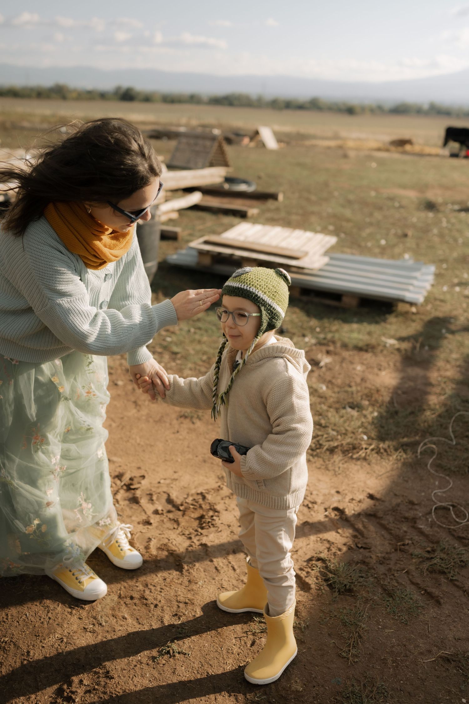 Two people in white protective suits stand together on dusty ground in warm sunlight at sunset.