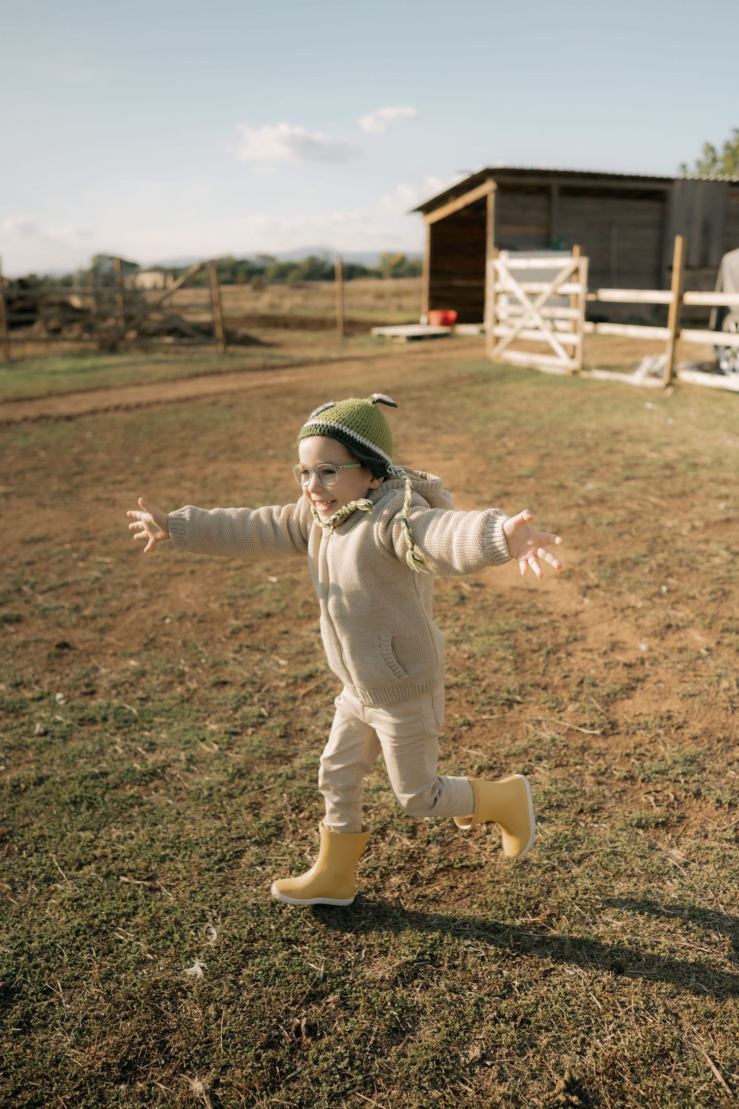A figure in white clothing performs a graceful dance-like movement sequence on a dirt field at sunset.