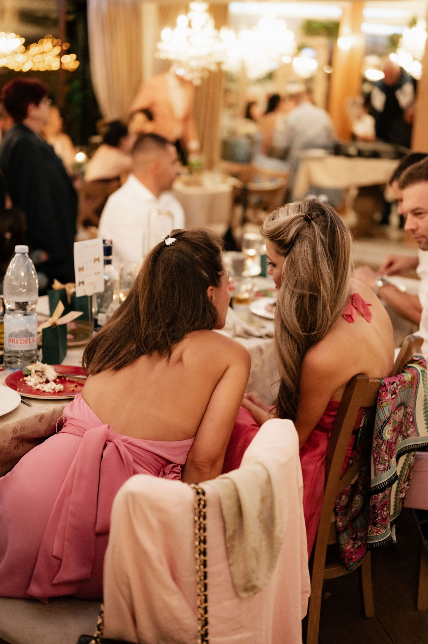 Guests seated at elegant dinner tables wearing pink and floral dresses creating a cohesive color scheme at formal event.