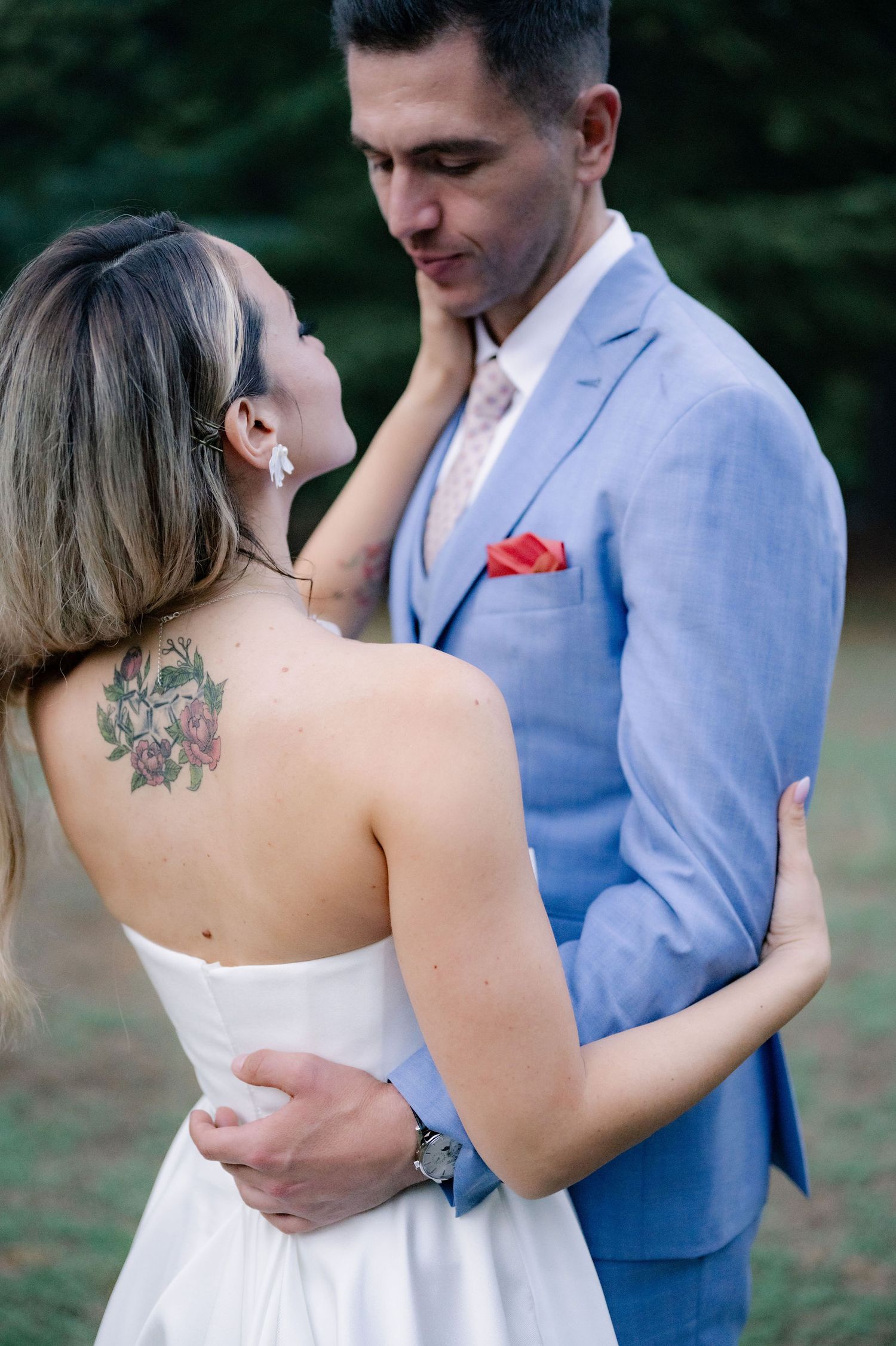 A romantic wedding couple in light blue suit and white dress share intimate dance poses outdoors.