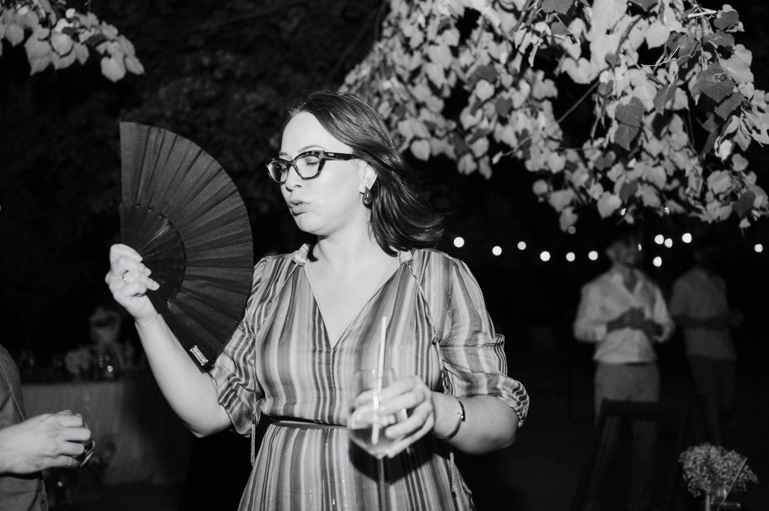 A sequence of black and white photos showing a person holding a fan and posing with orchid flowers in an artistic setting.