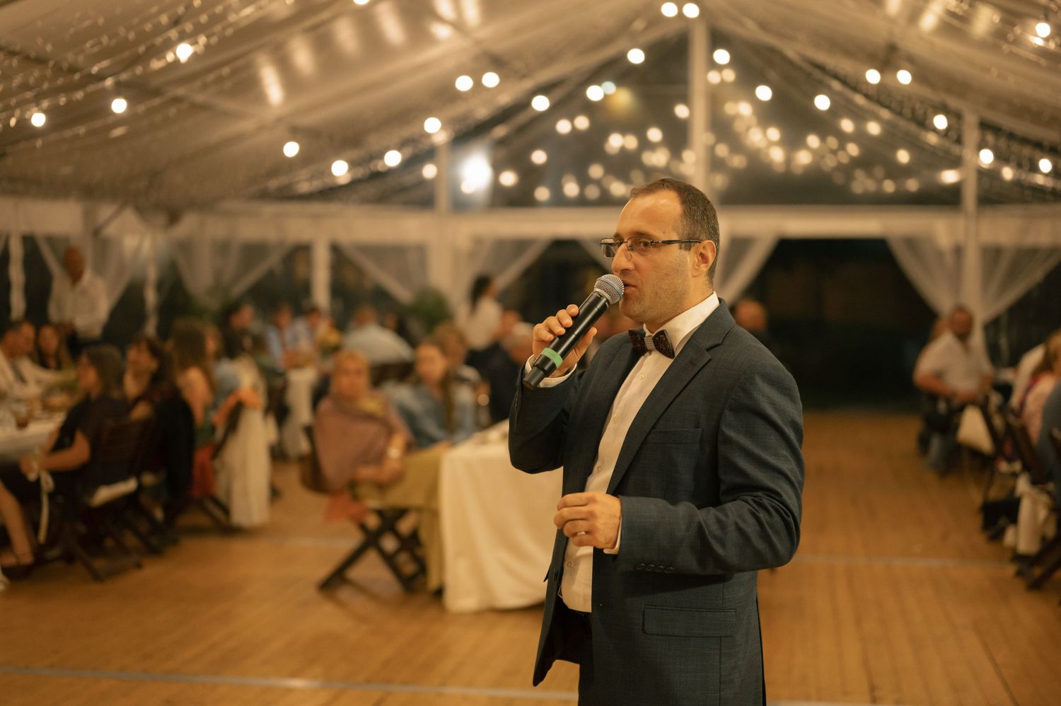 Wedding celebration in a barn-style venue with string lights and wooden beams overhead.