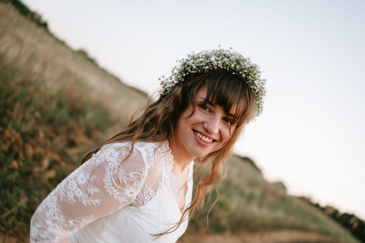 Joyful outdoor bridal portrait with baby's breath crown and lace dress.