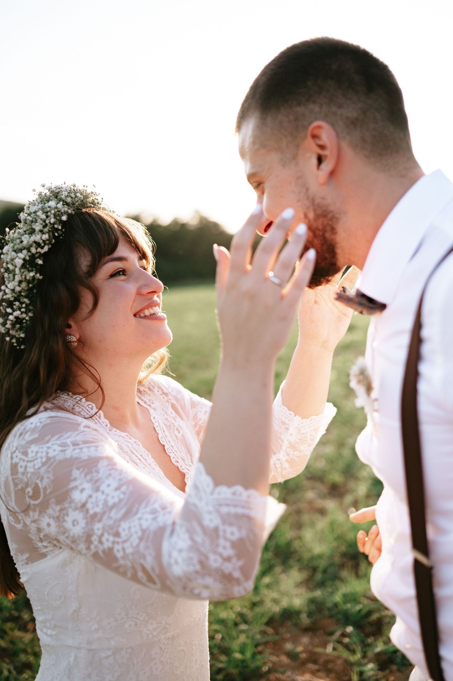 Joyful newlyweds share an intimate moment in golden sunset light among wildflowers.