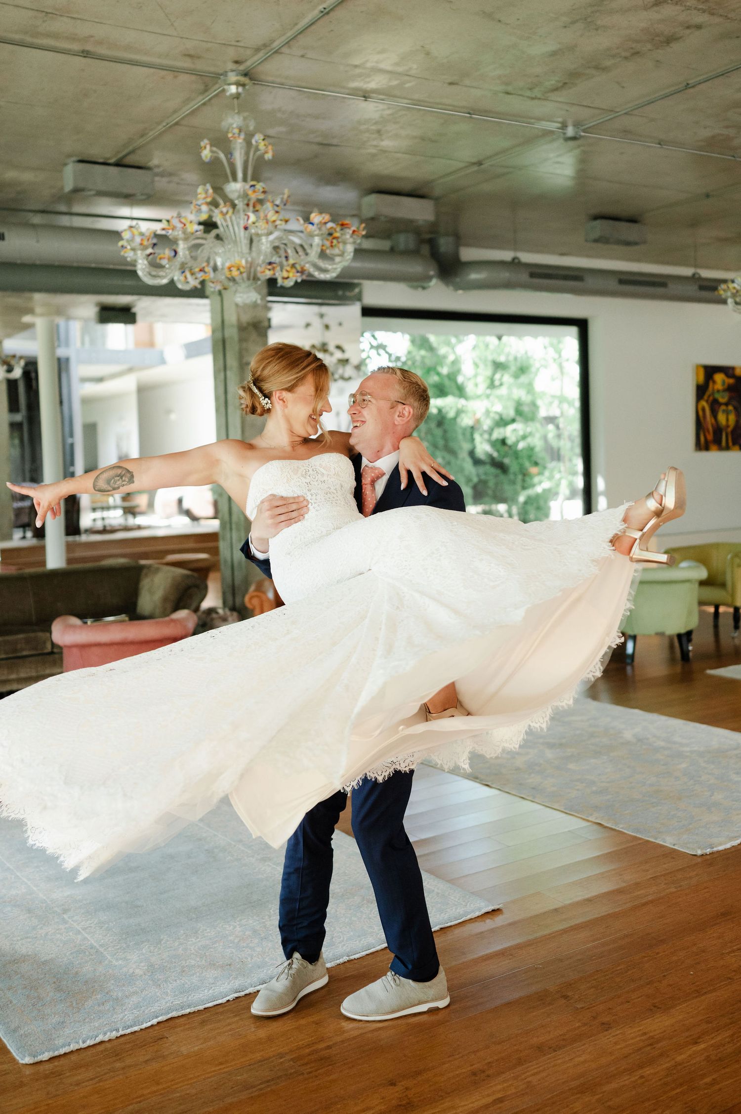 Groom lifts bride in flowing white dress during romantic wedding dance.