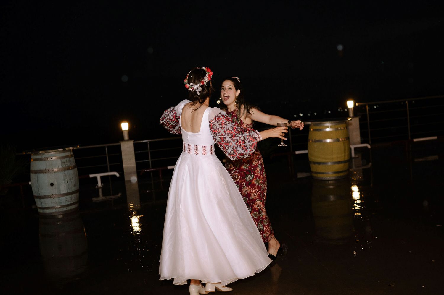 Wedding guests dance and celebrate together on a dark dance floor at an evening reception.