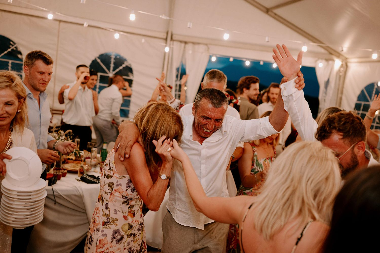 Guests enjoying themselves on a lively dance floor at an indoor wedding reception.